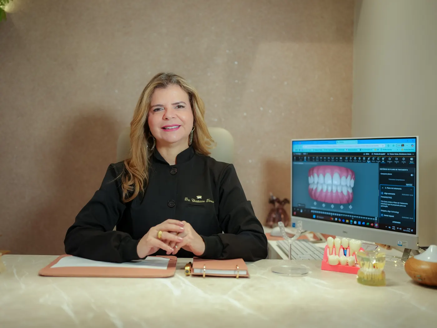 Dra. Christianne Tinoco no consultório, com a simulação 3D do alinhador na tela do computador